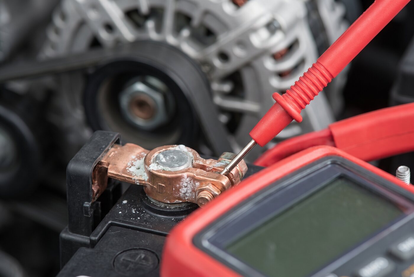 Car battery terminals being tested with a multimeter probe
